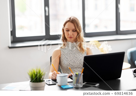 businesswoman writing to notebook at office businesswoman writing to notebook at office 69814636