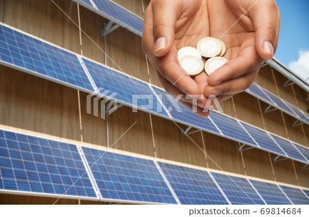 hands holding money over solar panels 69814684
