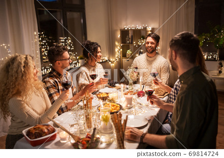 happy friends drinking red wine at christmas party 69814724