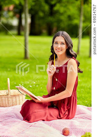 happy woman with diary and picnic basket at park happy woman with diary and picnic basket at park 69814767