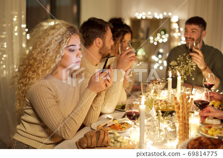 woman with smartphone at dinner party with friends woman with smartphone at dinner party with friends 69814775