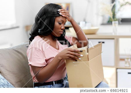 sad african american woman with parcel box at home sad african american woman with parcel box at home 69814921