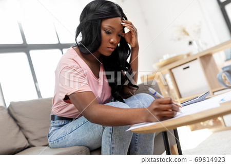 african woman with papers and calculator at home african woman with papers and calculator at home 69814923