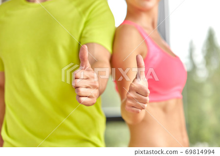close up of man and woman showing thumbs up in gym close up of man and woman showing thumbs up in gym 69814994