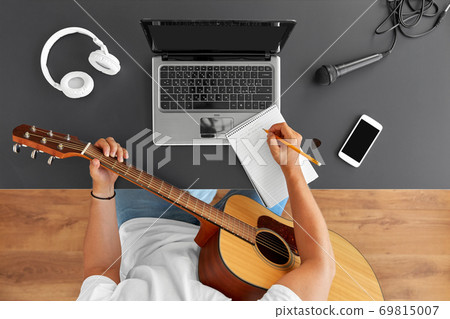 man with guitar writing to music book at table man with guitar writing to music book at table 69815007
