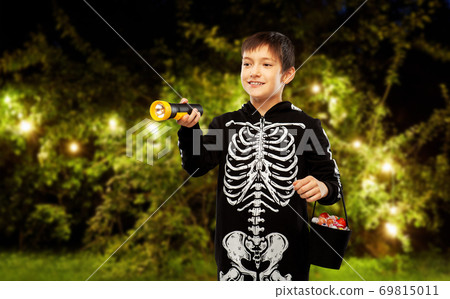 boy in halloween costume with candies and torch 69815011