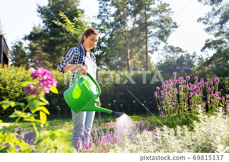 young woman watering flowers at garden young woman watering flowers at garden 69815137