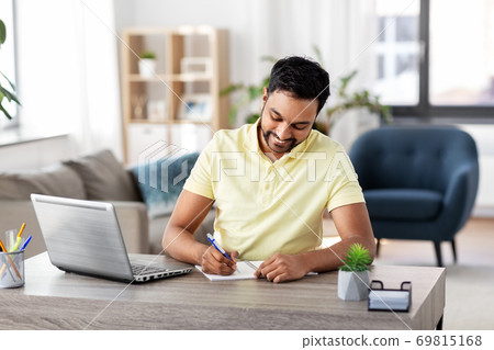 indian man with notebook and laptop at home office 69815168