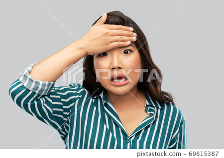 stressed asian woman holding to her head 69815387
