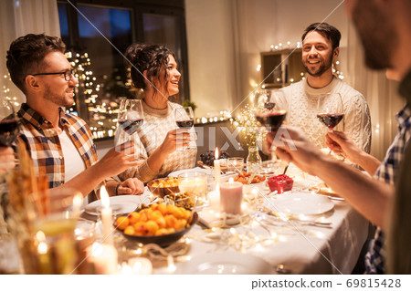 happy friends drinking red wine at christmas party 69815428