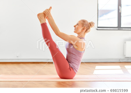 young woman doing both big toe pose at yoga studio young woman doing both big toe pose at yoga studio 69815599