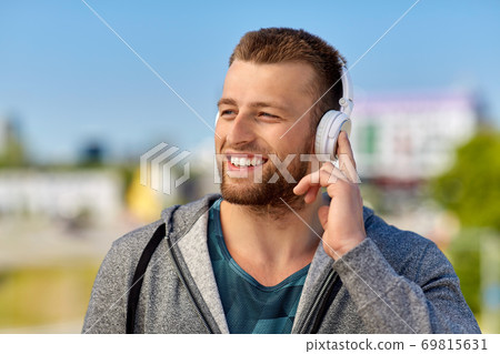 man in headphones listening to music outdoors 69815631