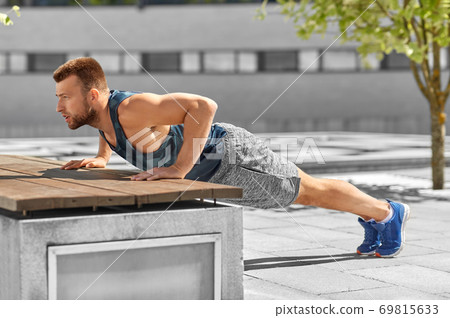 young man doing push ups on city street young man doing push ups on city street 69815633