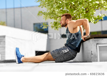 young man doing triceps dip on city street young man doing triceps dip on city street 69815636