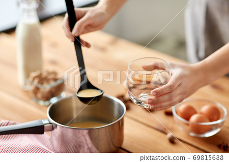 hands with ladle pouring eggnog from pot to glass hands with ladle pouring eggnog from pot to glass 69815688