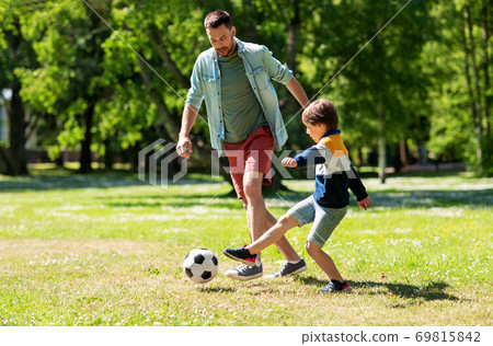 father with little son playing soccer at park father with little son playing soccer at park 69815842
