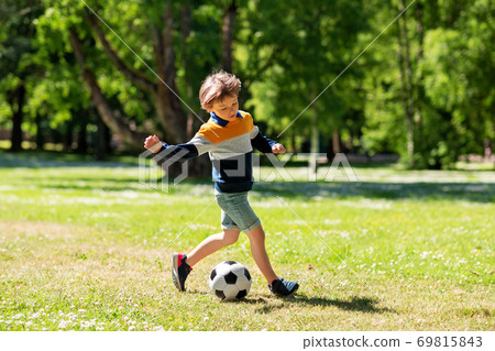 happy little boy with ball playing soccer at park happy little boy with ball playing soccer at park 69815843