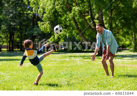 father with little son playing soccer at park father with little son playing soccer at park 69815844