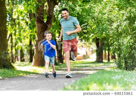 happy father and son compete in running at park happy father and son compete in running at park 69815861