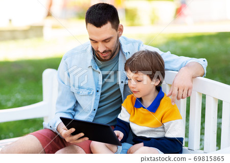 father and son with tablet pc computer at park father and son with tablet pc computer at park 69815865