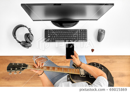 young man with guitar and smartphone at table young man with guitar and smartphone at table 69815869
