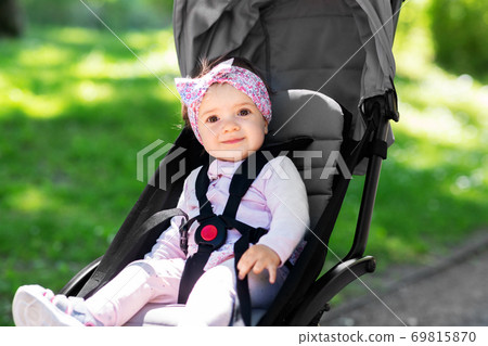 happy baby girl sitting in stroller at summer park 69815870