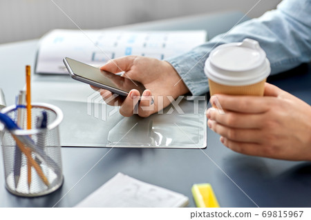 woman with coffee using smartphone at office 69815967