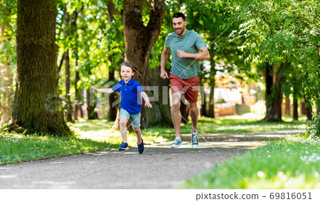 happy father and son compete in running at park happy father and son compete in running at park 69816051