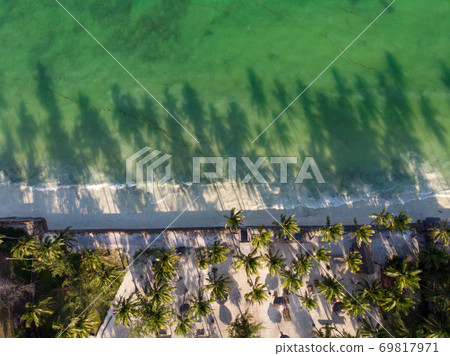 Aerial shot of a luxury hotel on a Beach first line with Palm Trees Drops their Shades on a High Tide Water of Indian Ocean at evening time in Paje village, Zanzibar, Tanzania Aerial shot of a luxury hotel on a Beach first line with Palm Trees Drops their Shades on a High Tide Water of Indian Ocean at evening time in Paje village, Zanzibar, Tanzania 69817971