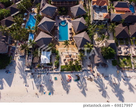 Aerial shot of a luxury hotel on a Beach first line with Palm Trees Garden at evening time in Paje village, Zanzibar, Tanzania Aerial shot of a luxury hotel on a Beach first line with Palm Trees Garden at evening time in Paje village, Zanzibar, Tanzania 69817997
