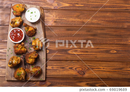 Chicken wings nuggets with sauces on wooden background . 69819689