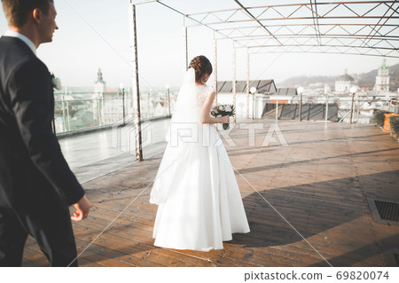 Stylish beautiful wedding couple kissing and hugging on background panoramic view of the old town Stylish beautiful wedding couple kissing and hugging on background panoramic view of the old town 69820074