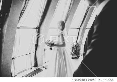 Lovely happy wedding couple, bride with long white dress posing in beautiful city Lovely happy wedding couple, bride with long white dress posing in beautiful city 69820090