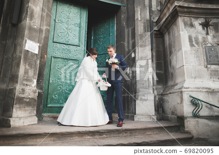 Lovely happy wedding couple, bride with long white dress posing in beautiful city Lovely happy wedding couple, bride with long white dress posing in beautiful city 69820095