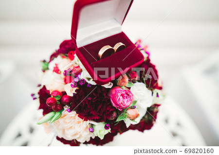 Beautiful toned picture with wedding rings against the background of a bouquet of flowers Beautiful toned picture with wedding rings against the background of a bouquet of flowers 69820160