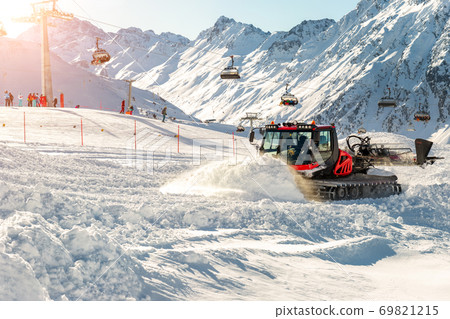 Red modern snowcat ratrack with snowplow snow grooming machine preparing ski slope piste hill at alpine skiing winter resort Ischgl in Austria. Heavy machinery mountain equipment track vehicle Red modern snowcat ratrack with snowplow snow grooming machine preparing ski slope piste hill at alpine skiing winter resort Ischgl in Austria. Heavy machinery mountain equipment track vehicle 69821215