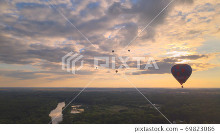 Aerial drone view of colorful hot air balloon flying over green park in small european city at summer sunset 69823086