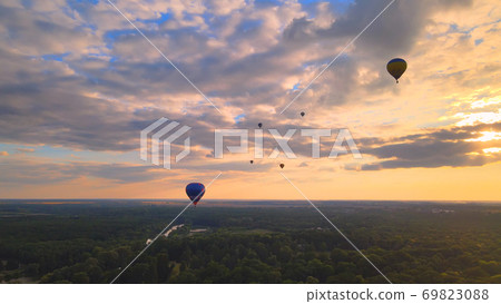 Aerial drone view of colorful hot air balloon flying over green park in small european city at summer sunset Aerial drone view of colorful hot air balloon flying over green park in small european city at summer sunset 69823088