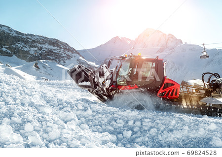 Red modern snowcat ratrack with snowplow snow grooming machine preparing ski slope piste hill at alpine skiing winter resort Ischgl in Austria. Heavy machinery mountain equipment track vehicle Red modern snowcat ratrack with snowplow snow grooming machine preparing ski slope piste hill at alpine skiing winter resort Ischgl in Austria. Heavy machinery mountain equipment track vehicle 69824528