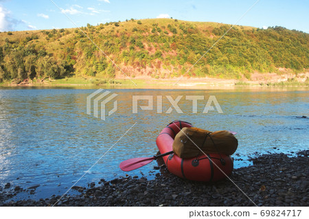 Orange packraft rubber boat with backpack on a river 69824717