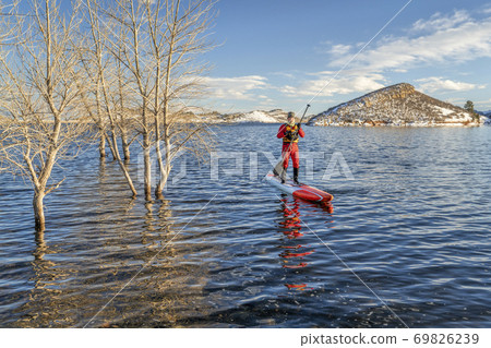 active senior is paddling stand up paddlenboard in winter active senior is paddling stand up paddlenboard in winter 69826239