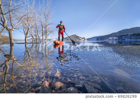 active senior is paddling stand up paddlenboard in winter 69826299