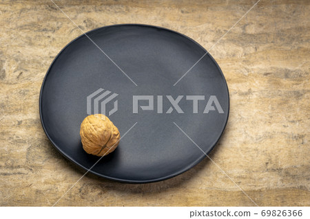 Single walnut on a black plate Single walnut on a black plate 69826366