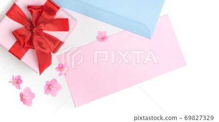 Pink gift box with red bow and blank greeting card for Valentine's day, love letter or wedding invitation. Top view. White background decorated with pink flowers. Pink gift box with red bow and blank greeting card for Valentine's day, love letter or wedding invitation. Top view. White background decorated with pink flowers. 69827329