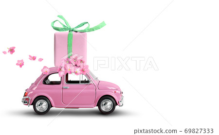 Pink toy car with gift box on a roof and flowers isolated on a white background. 69827333