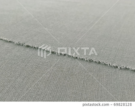 Ripped edge of fine fabric in gray. Loose threads at the edge of a piece of textile. Close-up. Woven background. Calm pastel color Ripped edge of fine fabric in gray. Loose threads at the edge of a piece of textile. Close-up. Woven background. Calm pastel color 69828128