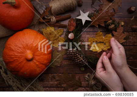 Children's hands hold a yellow leaf and make an autumn wreath 69830085