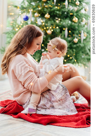 mother and daughter sitting at Christmas tree.  69830689