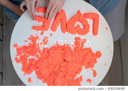 hand molded of red kinetic sand the word love. hand molded of red kinetic sand the word love. 69830690