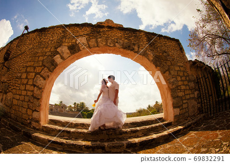 couple stand at old stone arch. honeymoon trip. couple stand at old stone arch. honeymoon trip. 69832291